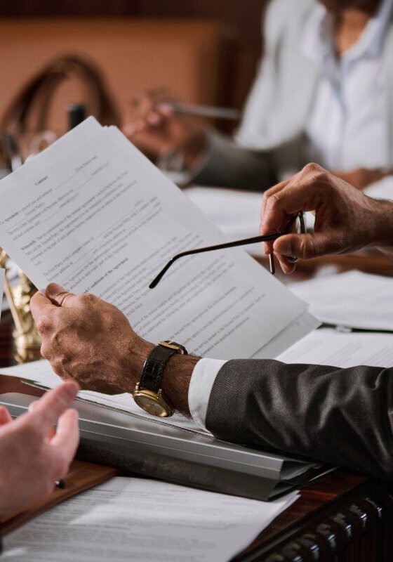 Ceo holding eyeglasses and contract Cropped shot of mature male ceo with eyeglasses in hand holding paper document over workplace while discussing main points of contract